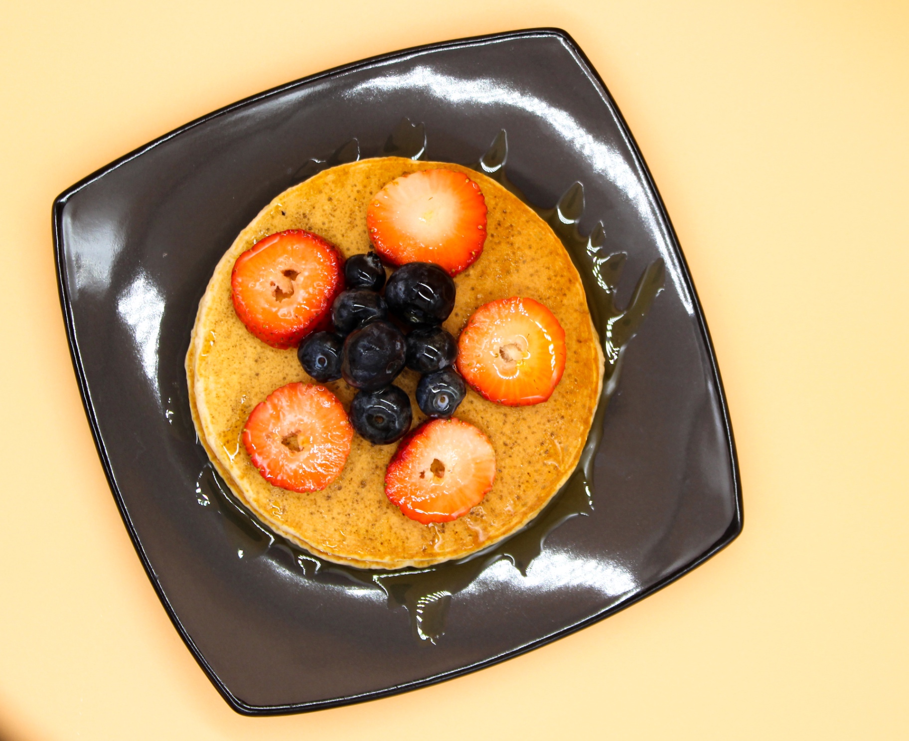 Single pancake topped with fresh berries and syrup