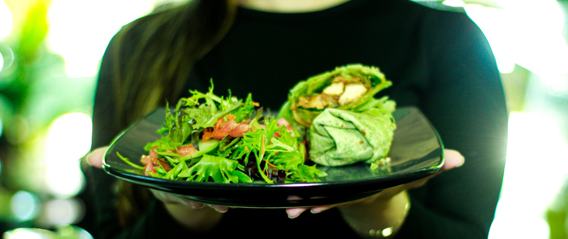 Fresh wrap with side salad on a black plate